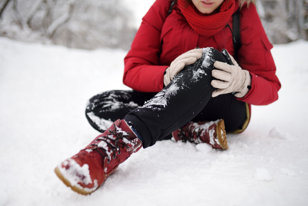 woman grabbing injured knee after slipping on ice